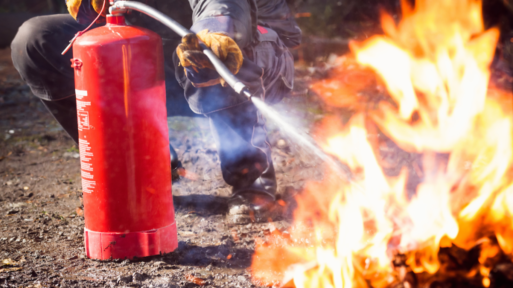 a guy using a fire extinguisher to put out a fire